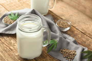 Jar with hemp milk on wooden table