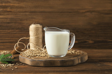 Jug with healthy hemp milk on wooden table