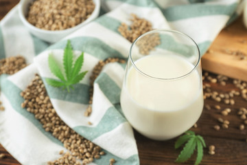 Glass with hemp milk on wooden background