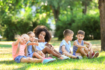 Naklejka na ściany i meble Group of children sitting on grass in park