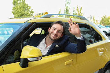 Male taxi driver sitting in yellow car