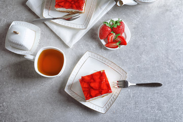 Plate with strawberry pretzel salad and cup of tea on table