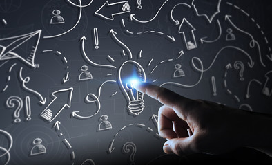 Businessman touching hand drawn lightbulb and arrows with his finger