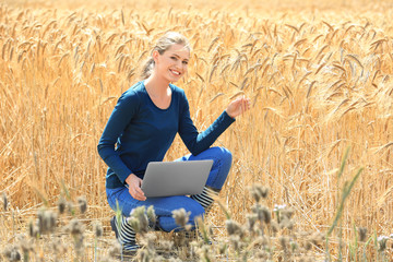 Naklejka na ściany i meble Agronomist using laptop in wheat field