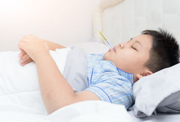 sick boy with thermometer sleep on bed
