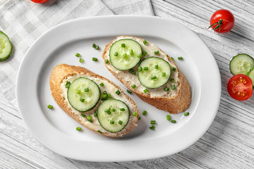 Plate of tasty sandwiches with fresh cucumber on table