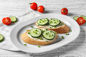 Plate of tasty sandwiches with fresh cucumber on table