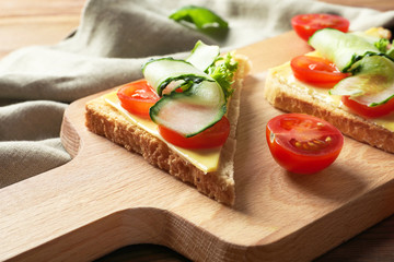 Tasty sandwiches with fresh cucumber on wooden board