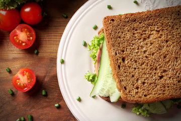 Plate of tasty sandwich with fresh cucumber on table