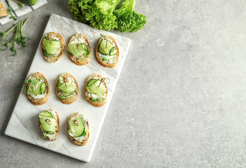 Set of delicious canapes with fresh cucumber on board