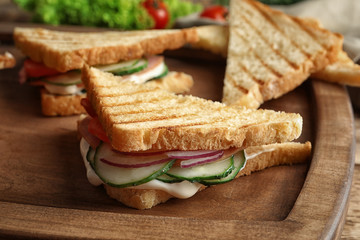 Tasty sandwiches with fresh cucumber on wooden board