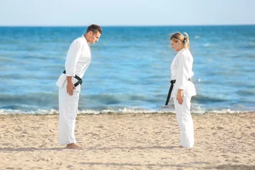 Photo sur Plexiglas Arts martiaux Young man and woman performing ritual bow prior to practicing karate outdoors