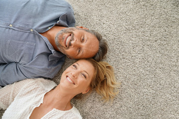 Upper view of cheerful couple laying on carpet