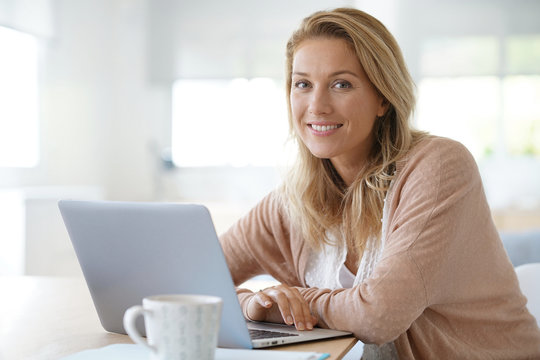 Attractive blond woman working on laptop computer at home