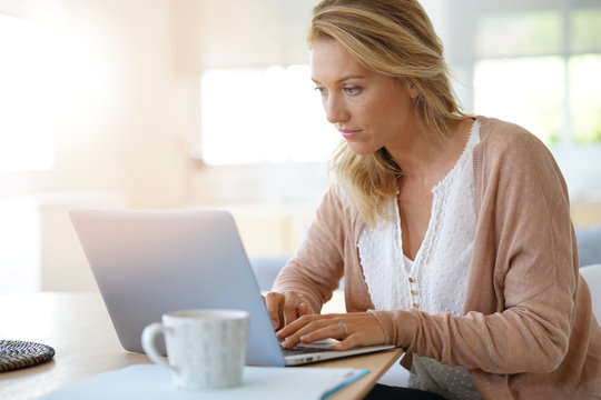 Attractive blond woman working on laptop computer at home
