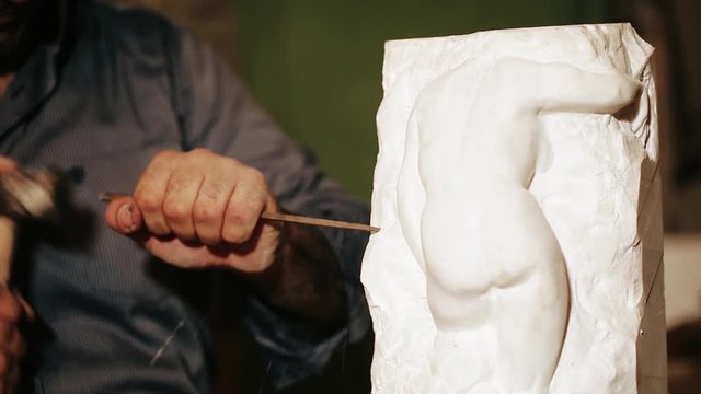 Sculptor works with marble statuette 