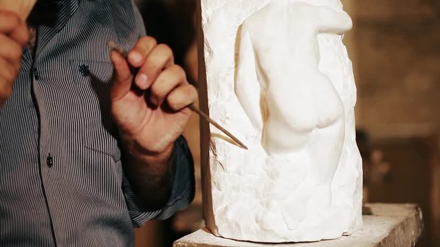 Sculptor works with marble statuette 