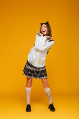 Full length portrait of a joyful teenage schoolgirl in uniform