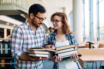 Young attractive students spending time in library
