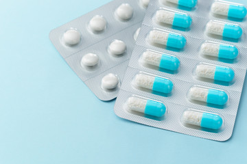 Blue capsule medicines and pills on blue background. Prescription drugs with copy space.
