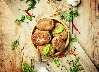 Homemade beef cutlets or meatballs in a bowl,  vintage wooden background, top view