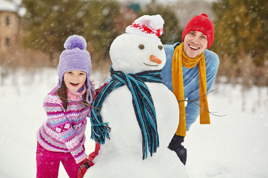 Father and daughter with snowman