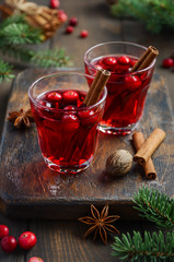 Cranberry drink on wooden background decorated with fir branches, spices and fresh berries,...