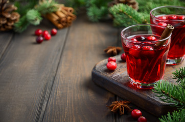 Cranberry drink on wooden background decorated with fir branches, spices and fresh berries,...
