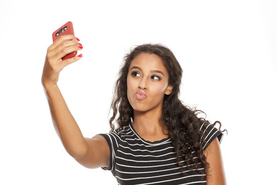 Young and beautiful dark skinned girl taking a selfies with her smartphone