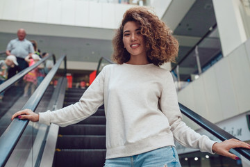 Curly haired girl with freckles in blank grey sweatshirt. Mock up.