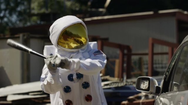  Aggressive astronaut smashing up car with a baseball bat.