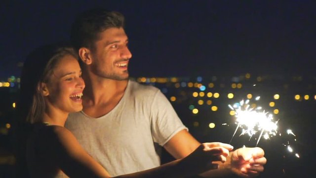 The happy couple hold bengal lights on a background of a night city. slow motion
