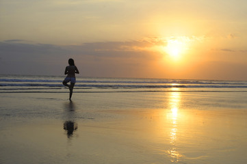 Naklejka premium woman meditating and thinking peacefully in yoga pose on desert beach on sunset in meditation and freedom
