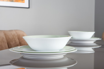 Beautiful empty plates with the green rim on the mirror table