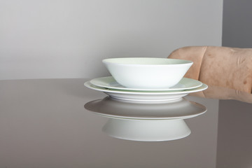 Beautiful empty plates with the green rim on the mirror table