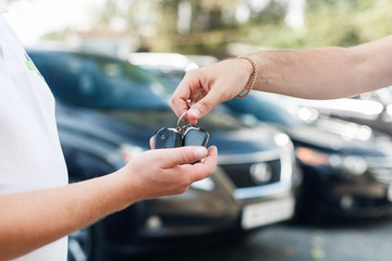 The owner of a new car getting the keys from the hands of the car dealer