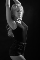 Naklejka premium beautiful young woman show her slim body on black background, monochrome