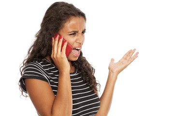 Fototapeta premium Young and serious dark skinned girl screaming on her smartphone