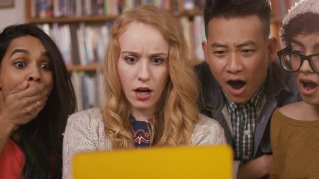 Student friends in shared accommodation reacting to something they see on tablet computer