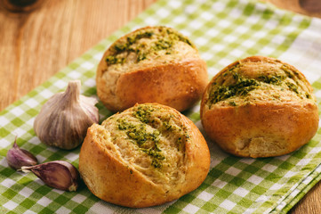 Homemade garlic bread rolls on wooden background.