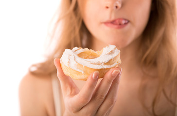 Young woman keeps in hand and eats cake with pleasure
