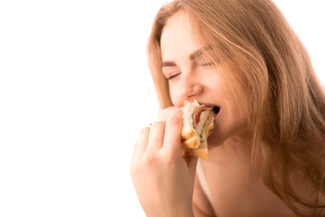 Young woman keeps in hand and eats sandwich with pleasure