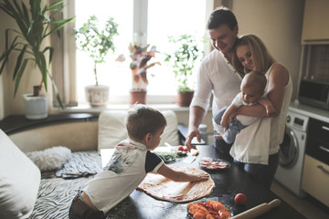 boy makes a pizza near loves parent