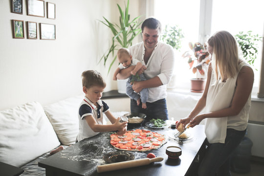 parents with two children prepare pizza in cozy
