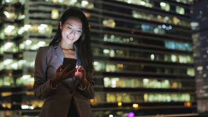 Business woman sending text message on cellphone at night