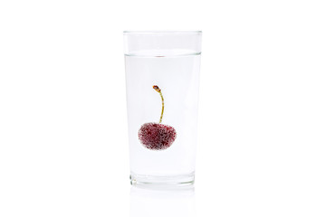 Cherry in a transparent glass with sparkling water isolated on white background