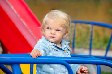 Fototapeta na wymiar Portrait of a blonde girl with blue eyes on a playground