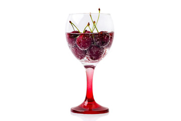 A glass of wine filled with sparkling water and berries of a ripe cherry isolated on a white background