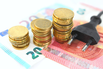 Electric plug with money and coins. Energy saving concept. Soft and selective focus.