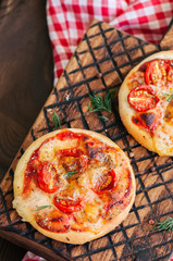 Mini pizzas margheritas on served on a wooden board. Wooden background